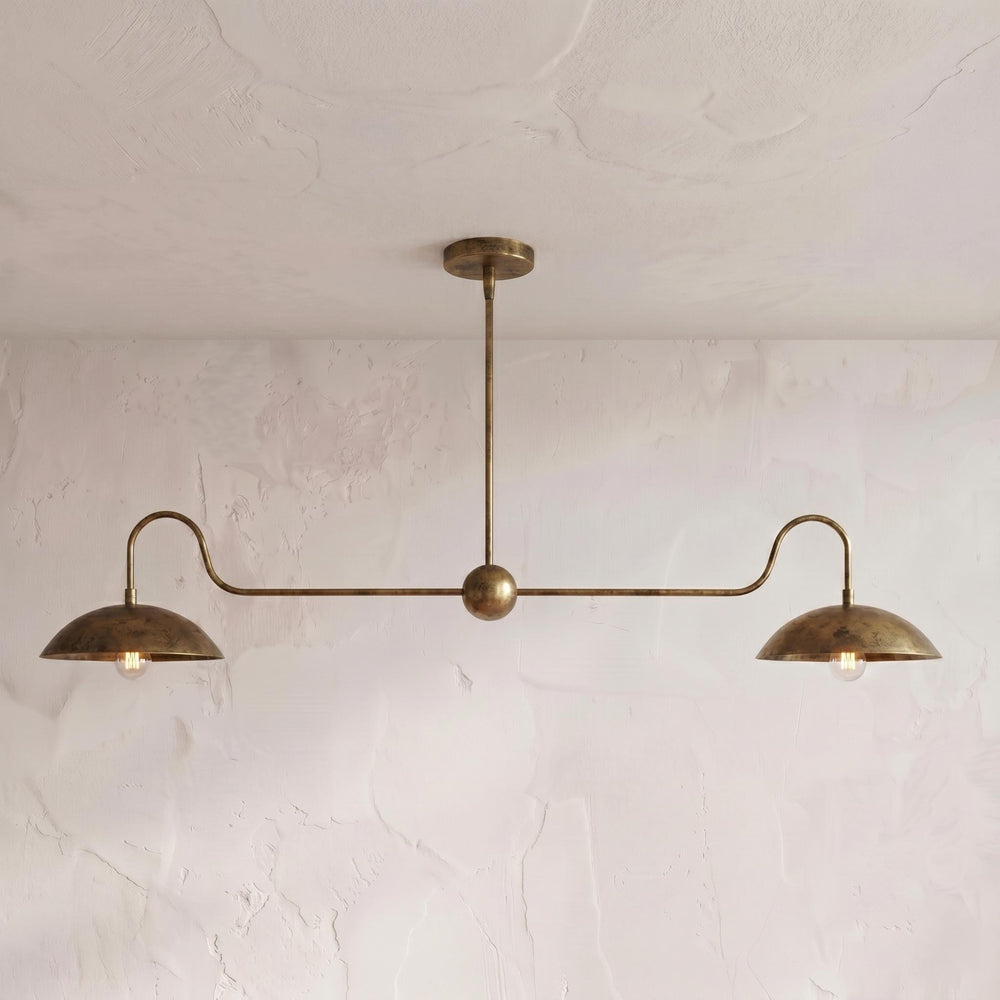 Sculptural brass double-dome pendant against a neutral wall